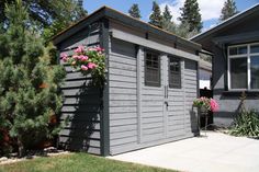 a gray shed with flowers growing out of it