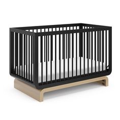 a black crib with white sheets on the bottom, and a wooden stand underneath it