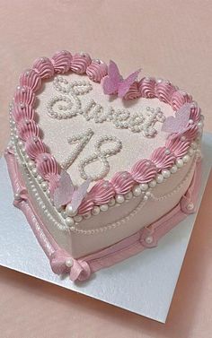 a pink heart shaped cake on top of a white card with butterfly decorations and pearls