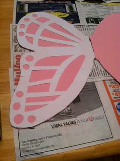 a pink paper butterfly sitting on top of a wooden table