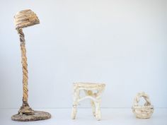 three pieces of driftwood are arranged in a row on a white surface, including a lamp and stool