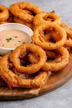 onion rings and dipping sauce on a wooden platter