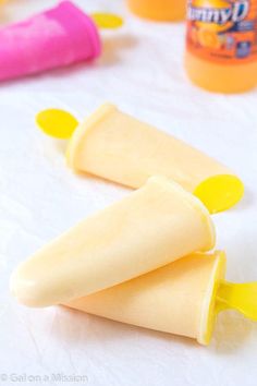 two popsicle shaped like bananas sitting on top of a table next to condiments