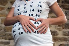 a pregnant woman holding her stomach with numbers on it