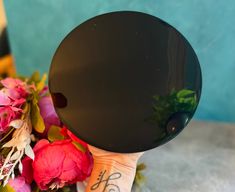 a person holding up a black object with flowers around it