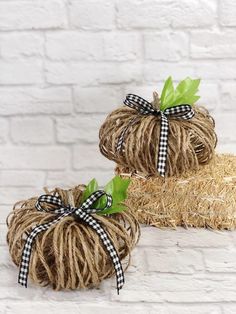 twine wrapped pumpkins with black and white bows are sitting on hay bales