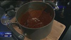 a pot filled with brown liquid sitting on top of a wooden cutting board