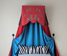 a bed with blue and red drapes on top of it's headboard