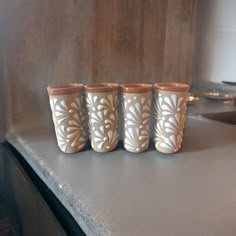 four cups sitting on top of a counter in front of a stove and microwave oven