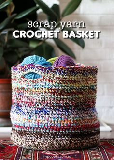 a colorful basket with yarn in it sitting on a table next to a potted plant