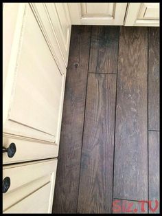 a wood floor with white cabinets and drawers