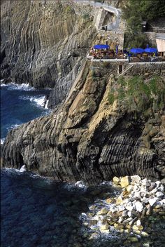 an aerial view of the ocean and rocky coastline with umbrellas set up on top