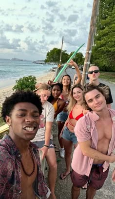 a group of people standing next to each other near the ocean with one person taking a selfie