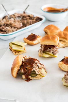 several sliders with meat and pickles on them are sitting on a white napkin