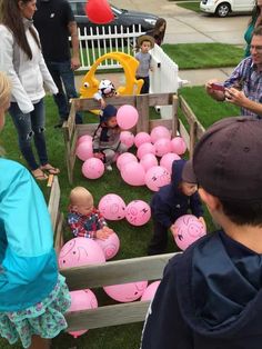 a group of people standing around pink piggy balls