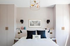 a white bed sitting under a chandelier in a bedroom next to two lamps