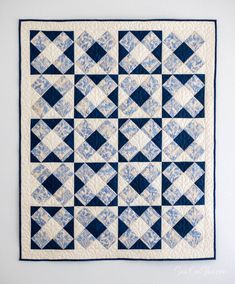 a blue and white quilt hanging on the wall