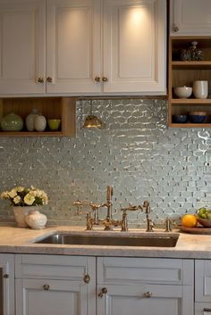 a kitchen with white cabinets and stainless steel backsplash tiles on the counter top