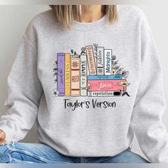 a woman wearing a sweatshirt that says taylor's version with books on the front