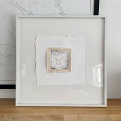 a white frame with a piece of paper in it on top of a wooden table