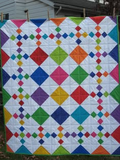 a colorful quilt hanging on a clothes line