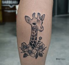 a giraffe with flowers on it's leg is seen in this tattoo