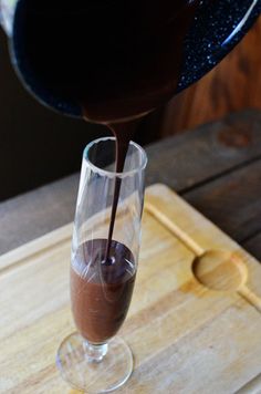 someone pouring chocolate into a glass on a cutting board