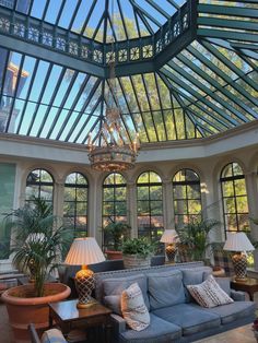 a living room filled with furniture and lots of windows covered in glass roof coverings