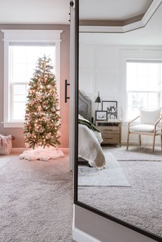 a living room with a christmas tree in the corner and a mirror on the wall