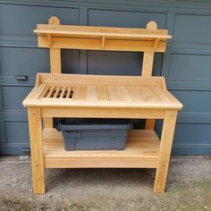 a wooden work bench sitting in front of a garage door next to a trash can