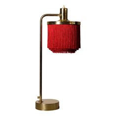 a red lamp with a gold base on a white background