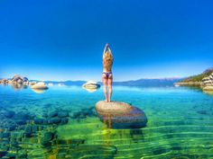 a woman standing on top of a rock in the water