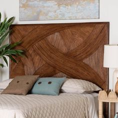 a bed that has some pillows on it and a plant in front of the headboard