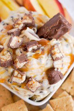 a bowl filled with ice cream next to crackers and an apple on the side