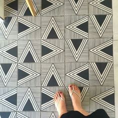 a person standing on the floor in front of a black and white wallpaper pattern