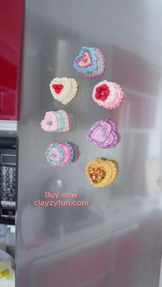 there are crocheted cupcakes on the side of a refrigerator door that is decorated with hearts