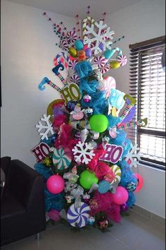 a brightly colored christmas tree decorated with balloons and snowflakes is in front of a window