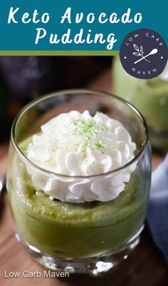 a green dessert with whipped cream in a glass bowl on a wooden table next to a clock