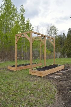 a wooden structure with plants in it on the side of a field next to trees