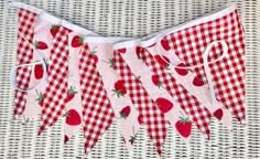 a red and white checkered table cloth with strawberries hanging from it's sides