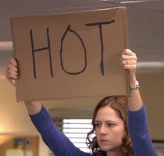 a woman holding up a box with the word hot written on it in front of her head