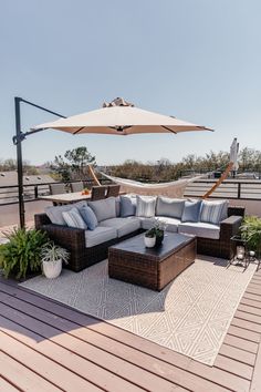 an outdoor living area with couches, tables and umbrellas on top of the roof