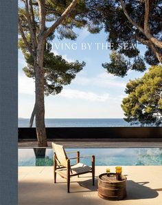 the cover of living by the sea, featuring a chair and table next to an outdoor pool