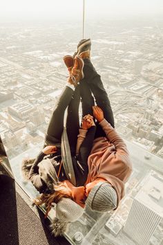 two people sitting on the edge of a glass floor in an office building looking down