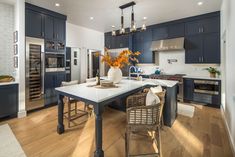 a large kitchen with blue cabinets and white counter tops, an island in the middle