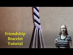 a woman standing in front of a wall holding a purple and black striped tie with the words friendship bracelet