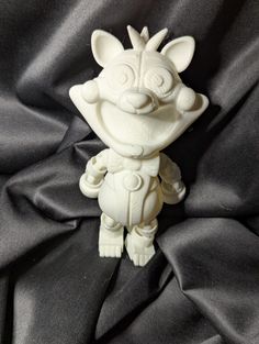 a white figurine sitting on top of a black cloth