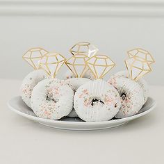 a white plate topped with donuts covered in sprinkles and gold decorations