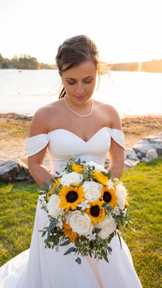 a woman in a wedding dress holding a bouquet of sunflowers