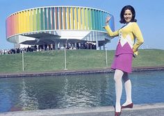 a woman standing in front of a rainbow colored building